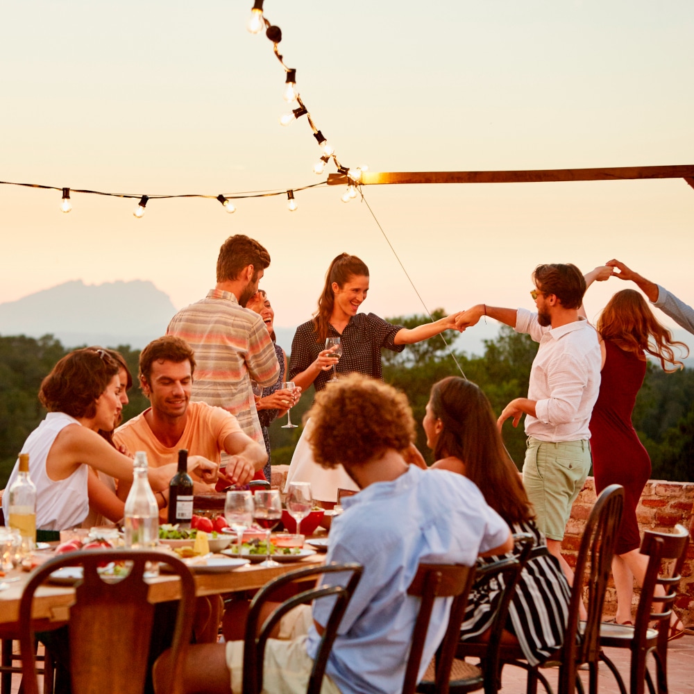 a group of friends gathers around a table outdoors