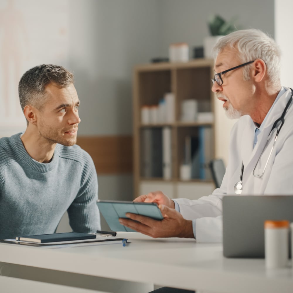 a doctor sits at his desk with a patient